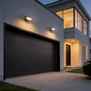 Solar powered motion sensor wall light illuminating a modern house entrance at dusk.