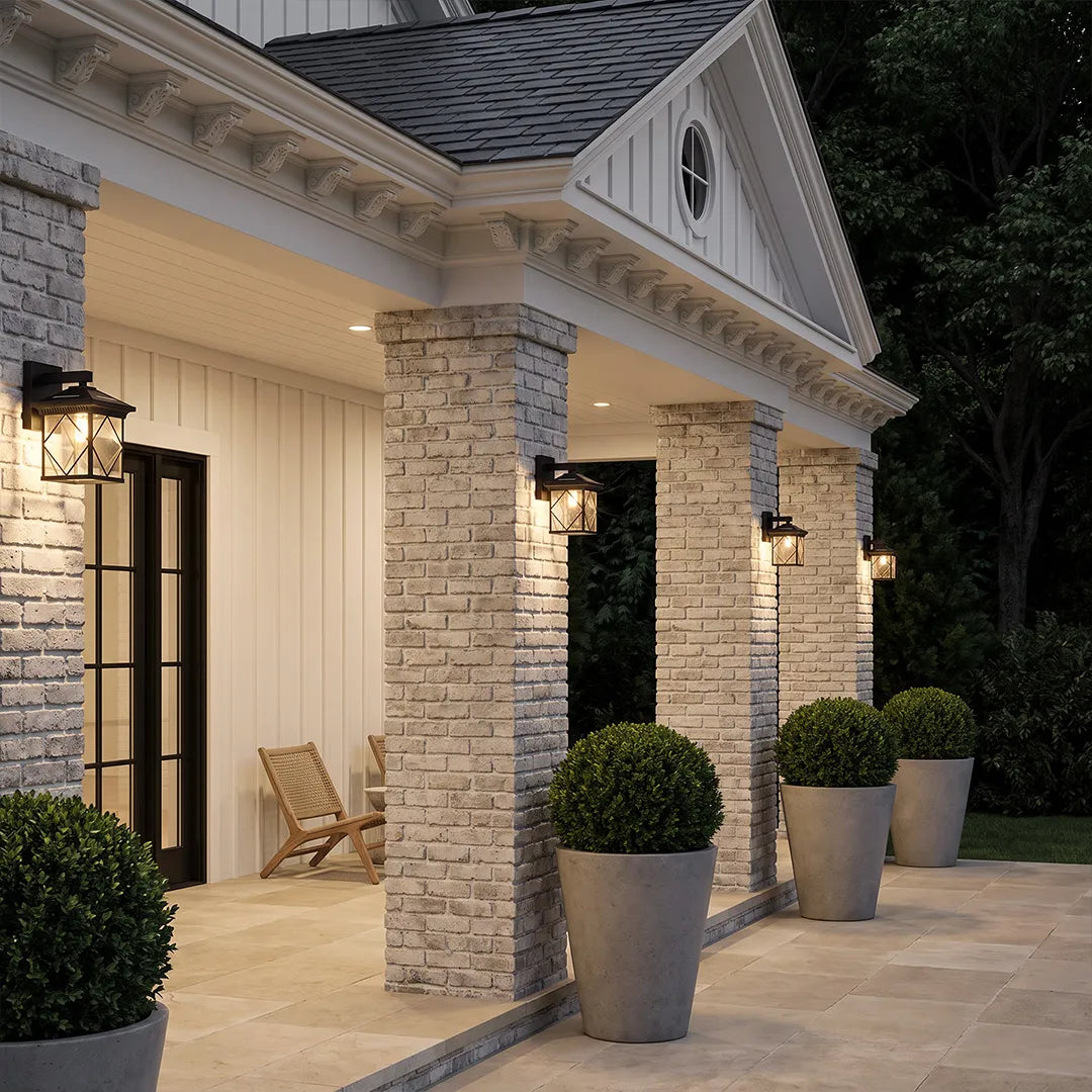 Solar powered outdoor wall sconces illuminating a covered porch with stone columns at dusk.