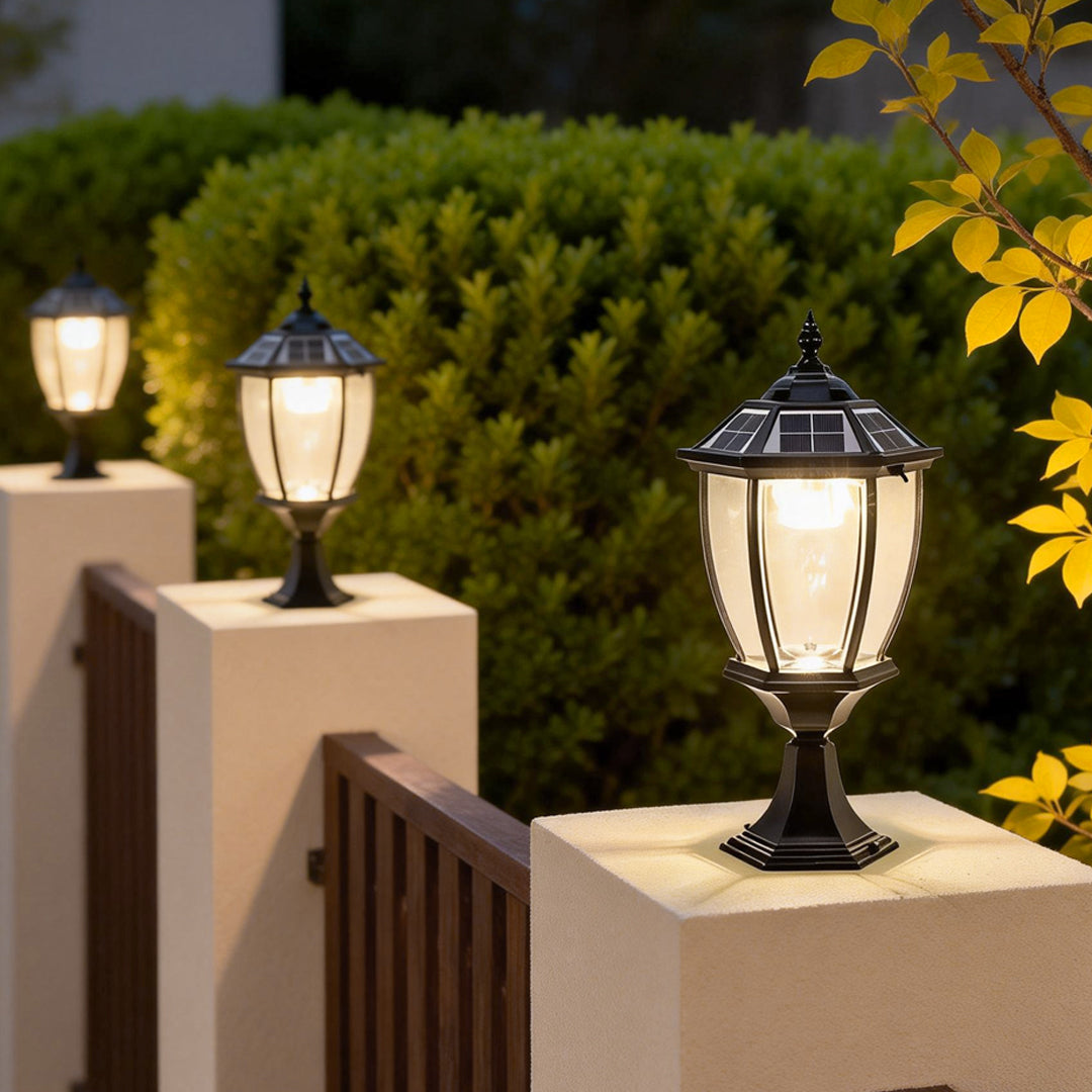 Solar powered pillar lights providing soft illumination along a landscaped fence.