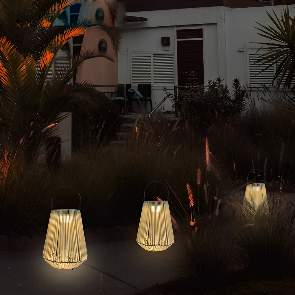 Hanging solar rope lanterns illuminating a garden corner with ornamental grasses at dusk.