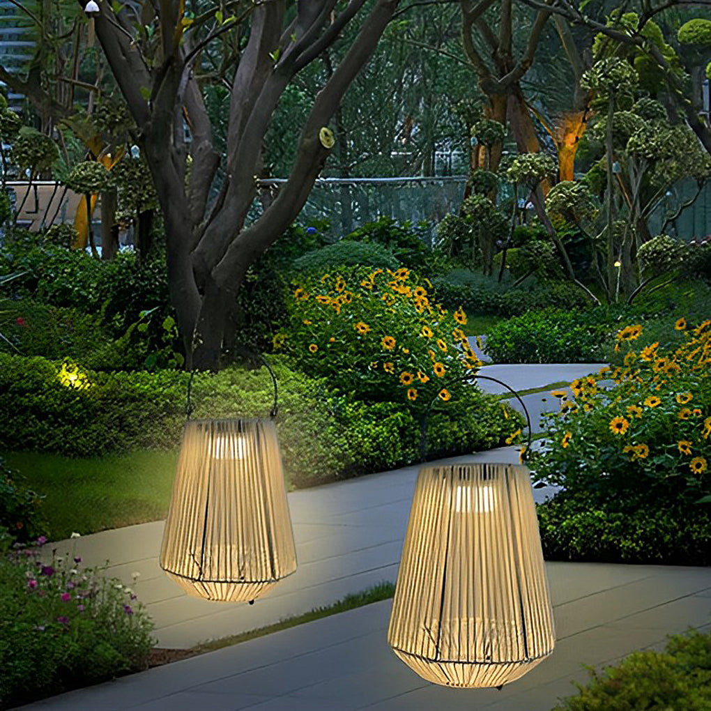 Solar powered rope lantern lighting a garden pathway surrounded by trees and flowering plants.
