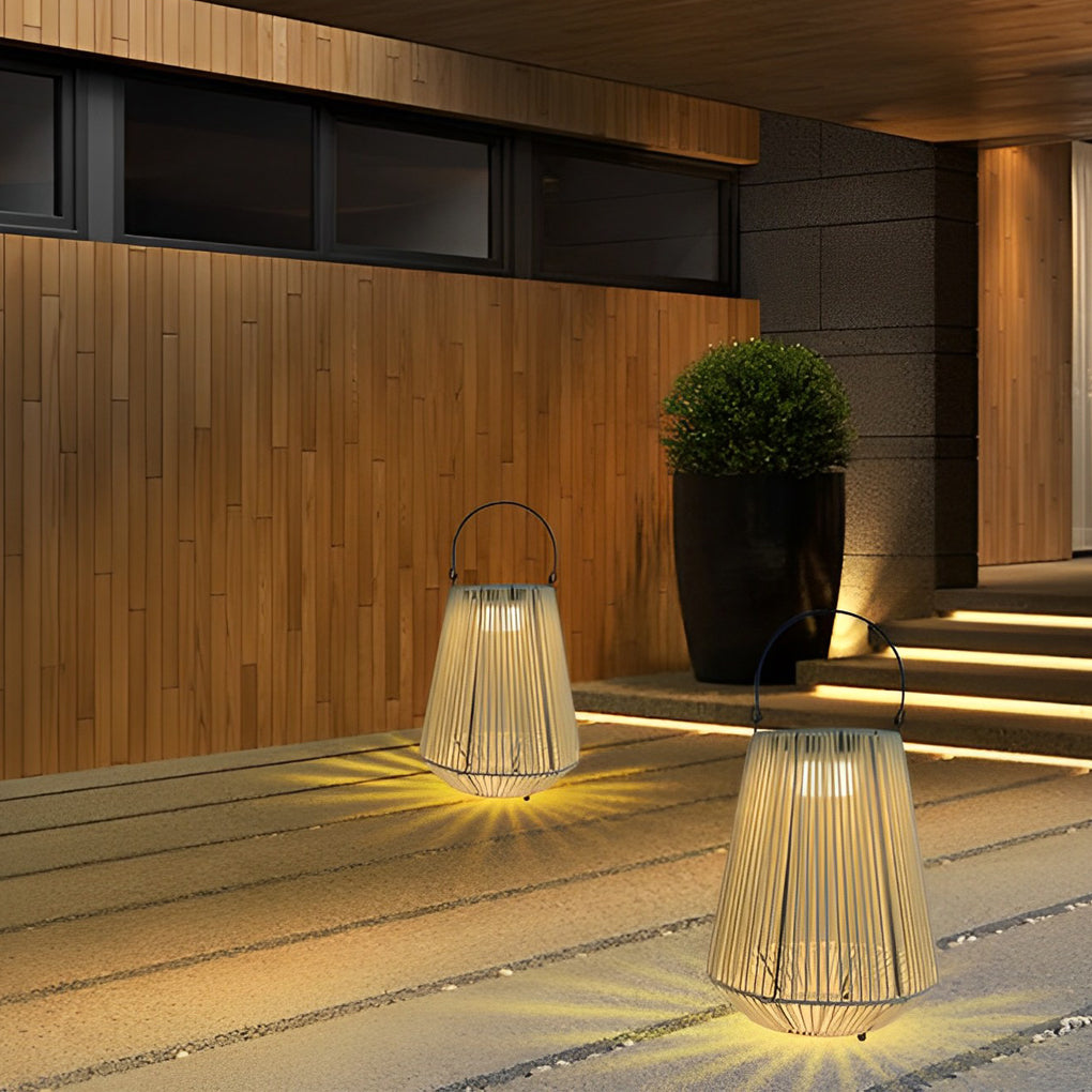 Multiple solar powered rope lanterns placed on a minimalist concrete patio near a wooden wall.