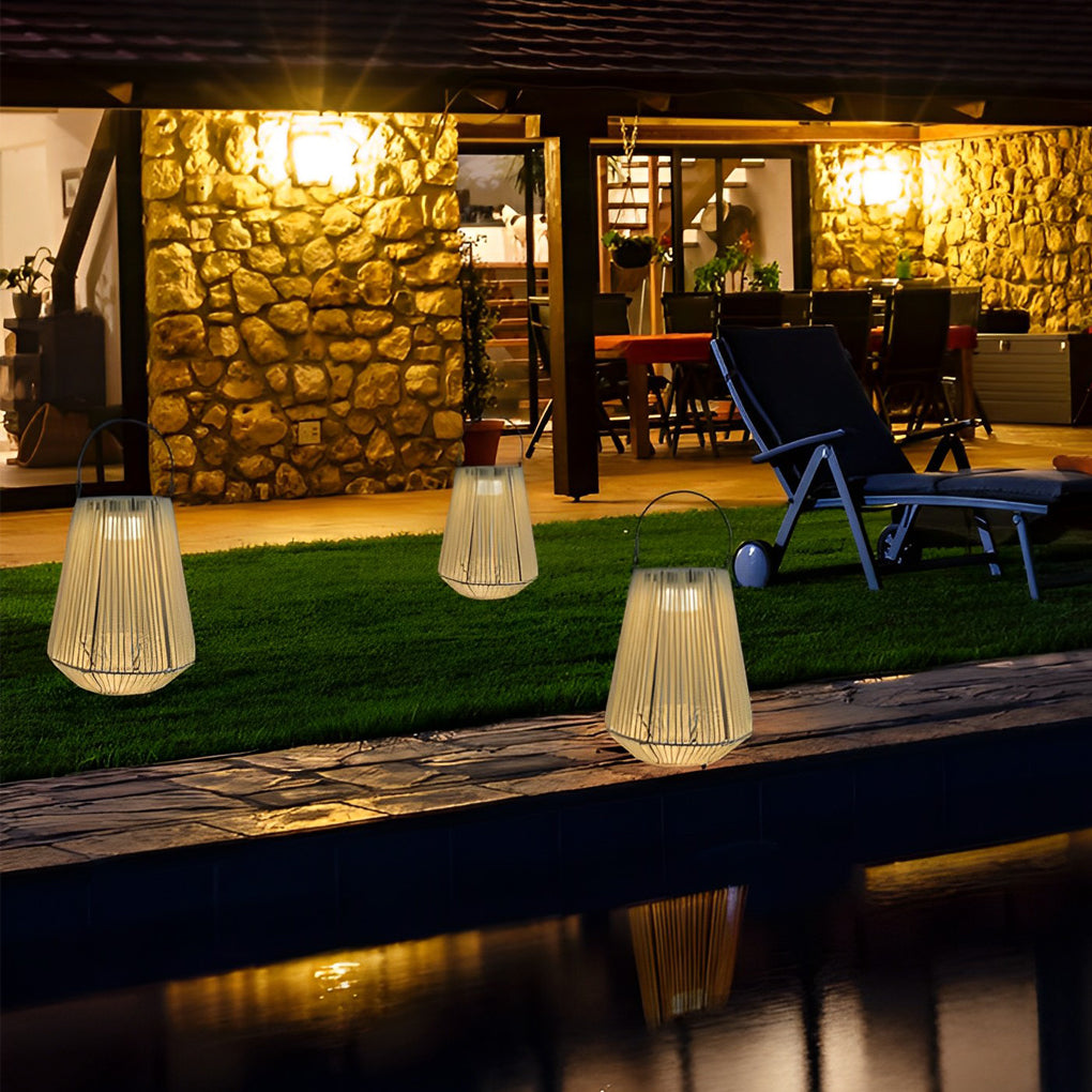 Solar powered rope lanterns positioned near a poolside lawn and outdoor seating area at night.