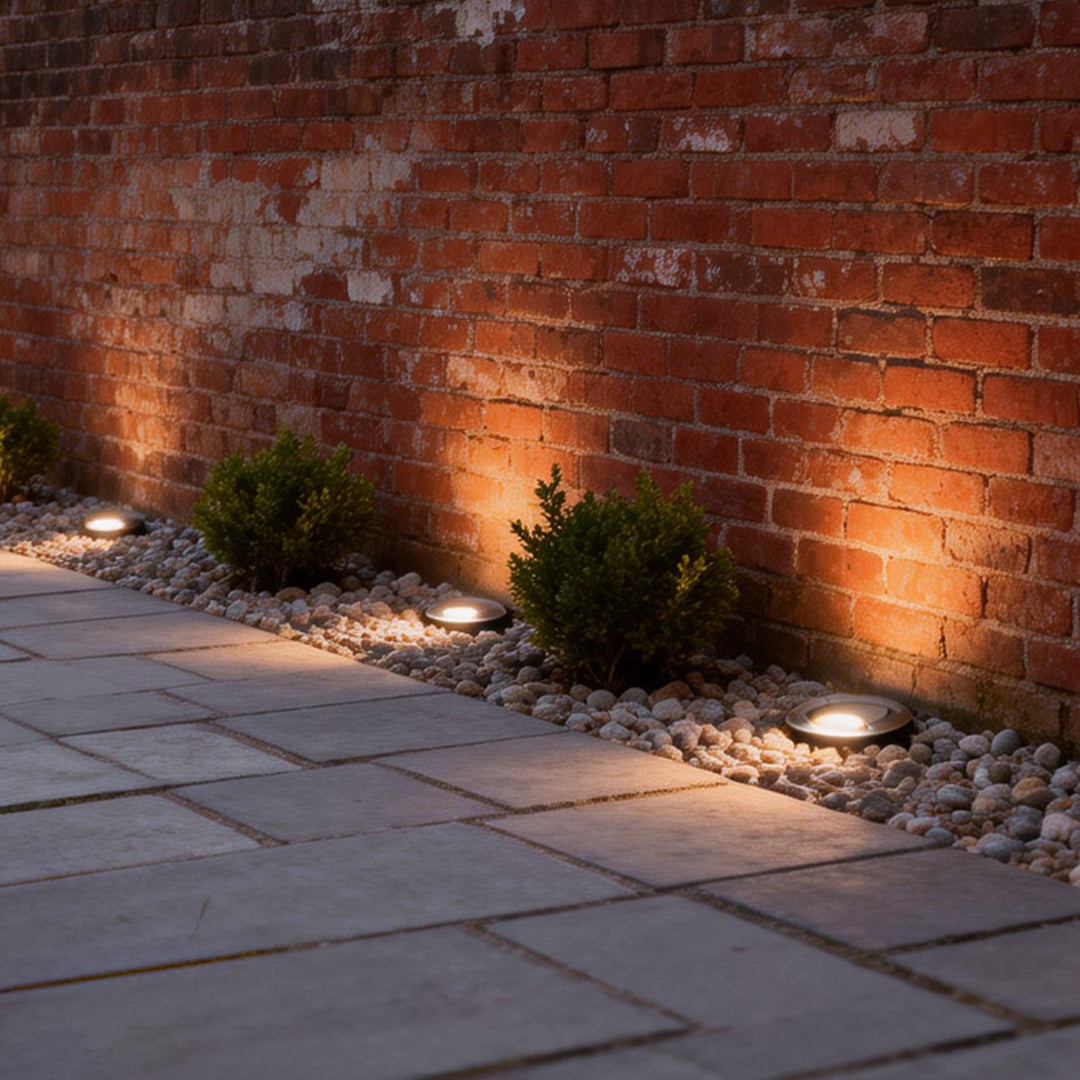 Solar powered well lights illuminating a modern brick garden pathway with warm ambient glow.