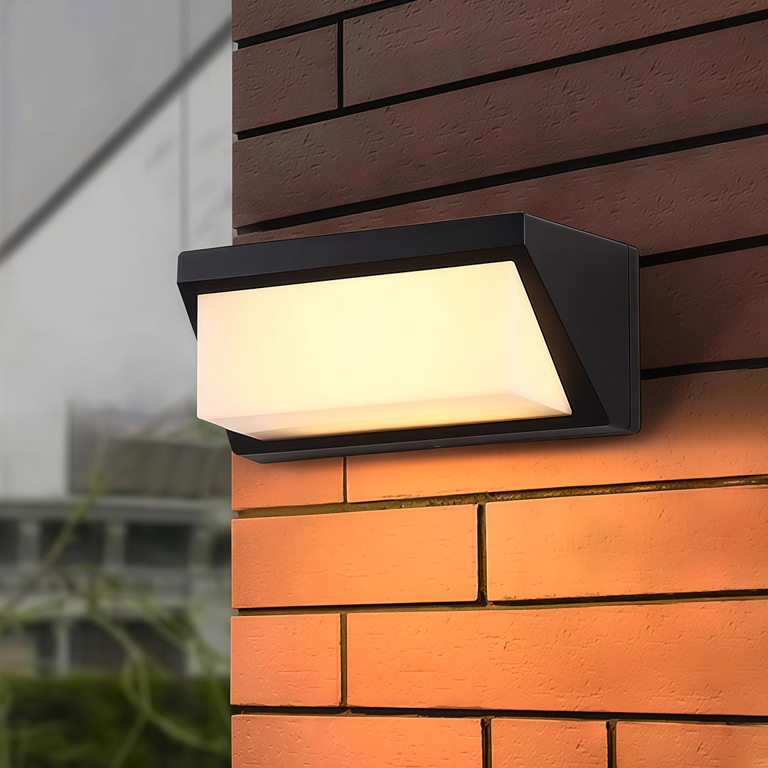 Modern solar outdoor wall mount light illuminating a path, installed on a concrete wall to enhance nighttime visibility.