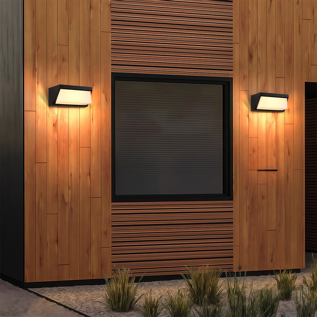 Stylish solar outdoor wall mount light providing soft illumination in a modern garden, mounted on a stone wall.