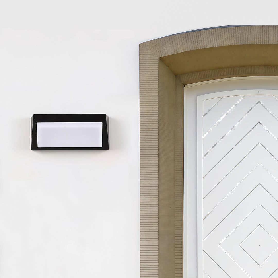 Black solar wall light installed on a modern wooden fence, creating a cozy lighting effect for an outdoor space.