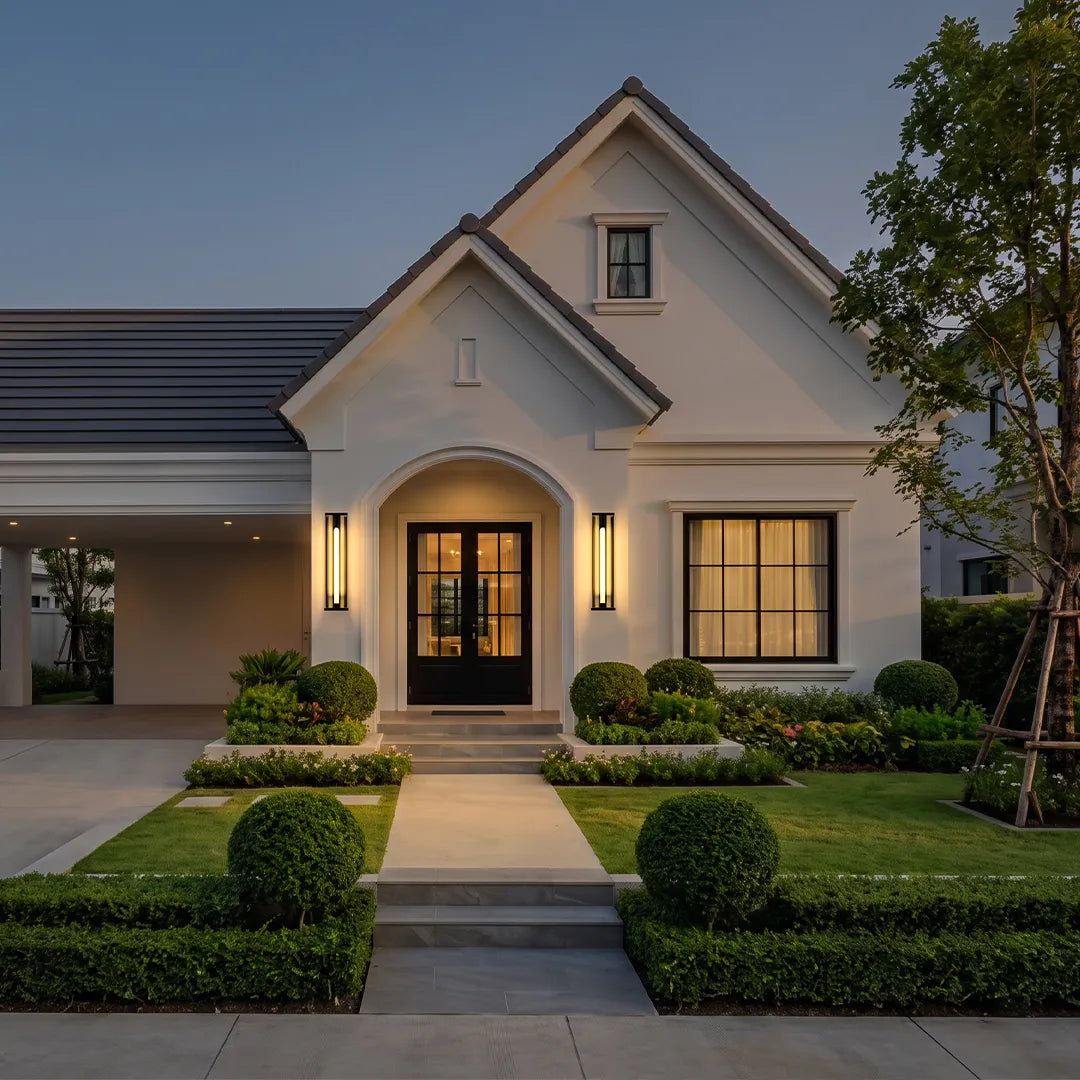 Solar wall sconce with warm glow beside modern home entrance and landscaped garden
