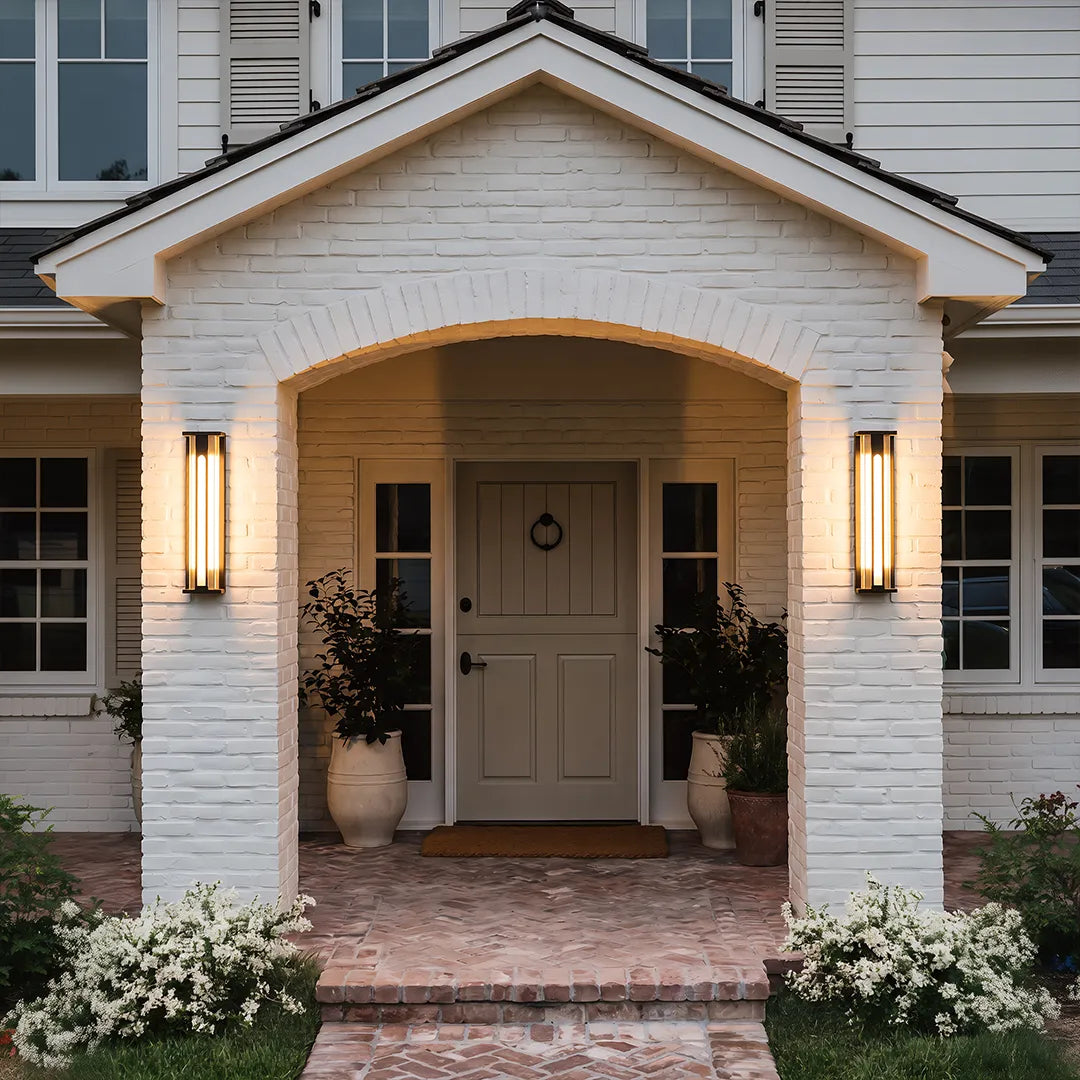 Solar wall sconces with warm lighting beside elegant front door and white brick wall
