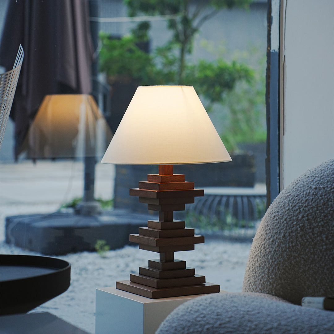 Solid wood table lamp with stacked wood base and warm light on patio table.