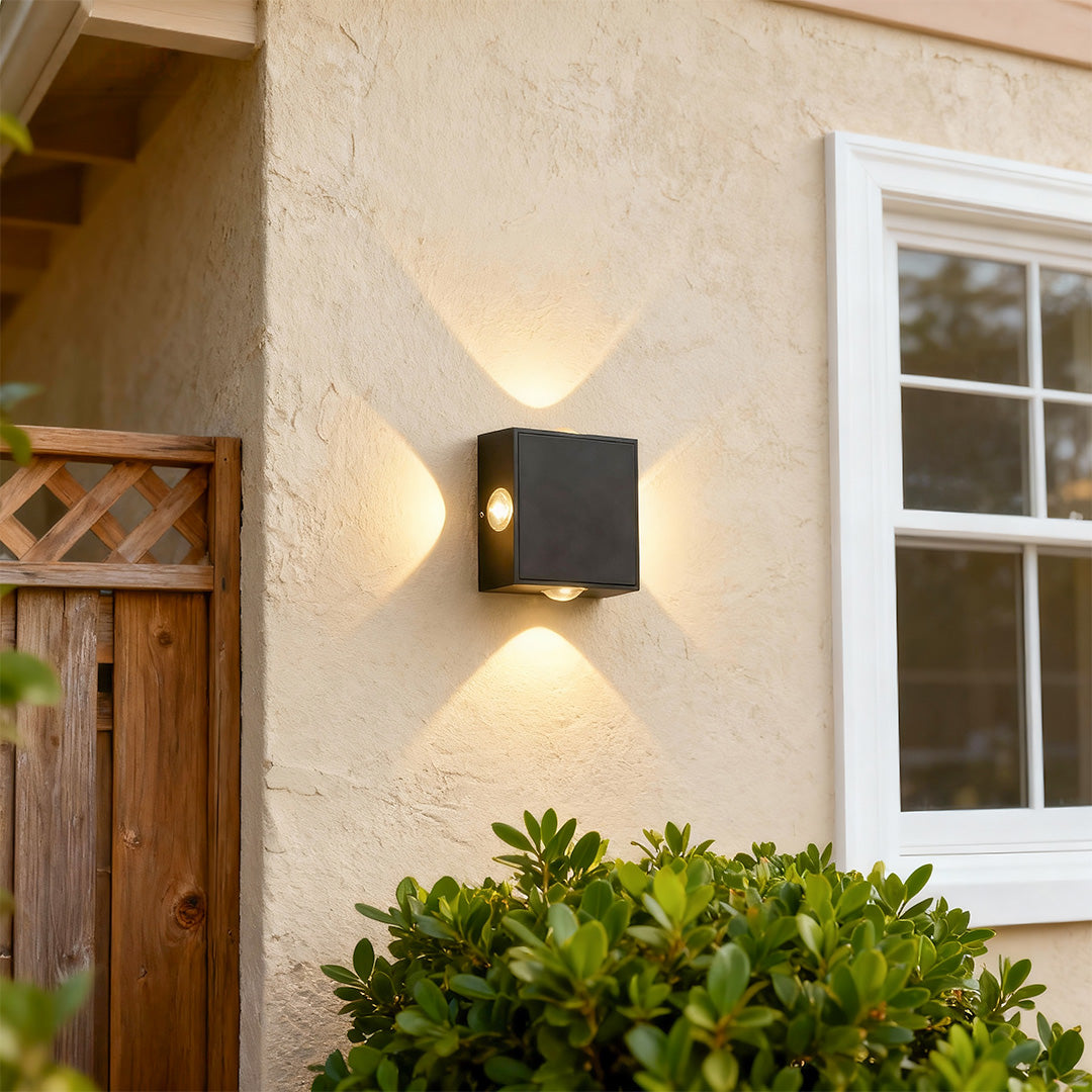 Sophisticated black outdoor sconce light featuring glass shade chandelier influence with bidirectional glow on neutral stucco wall.