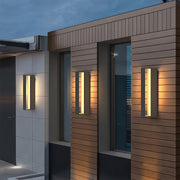 Sophisticated black sconces outdoor with glass shade chandelier influence providing architectural accent lighting on modern brick and concrete building.