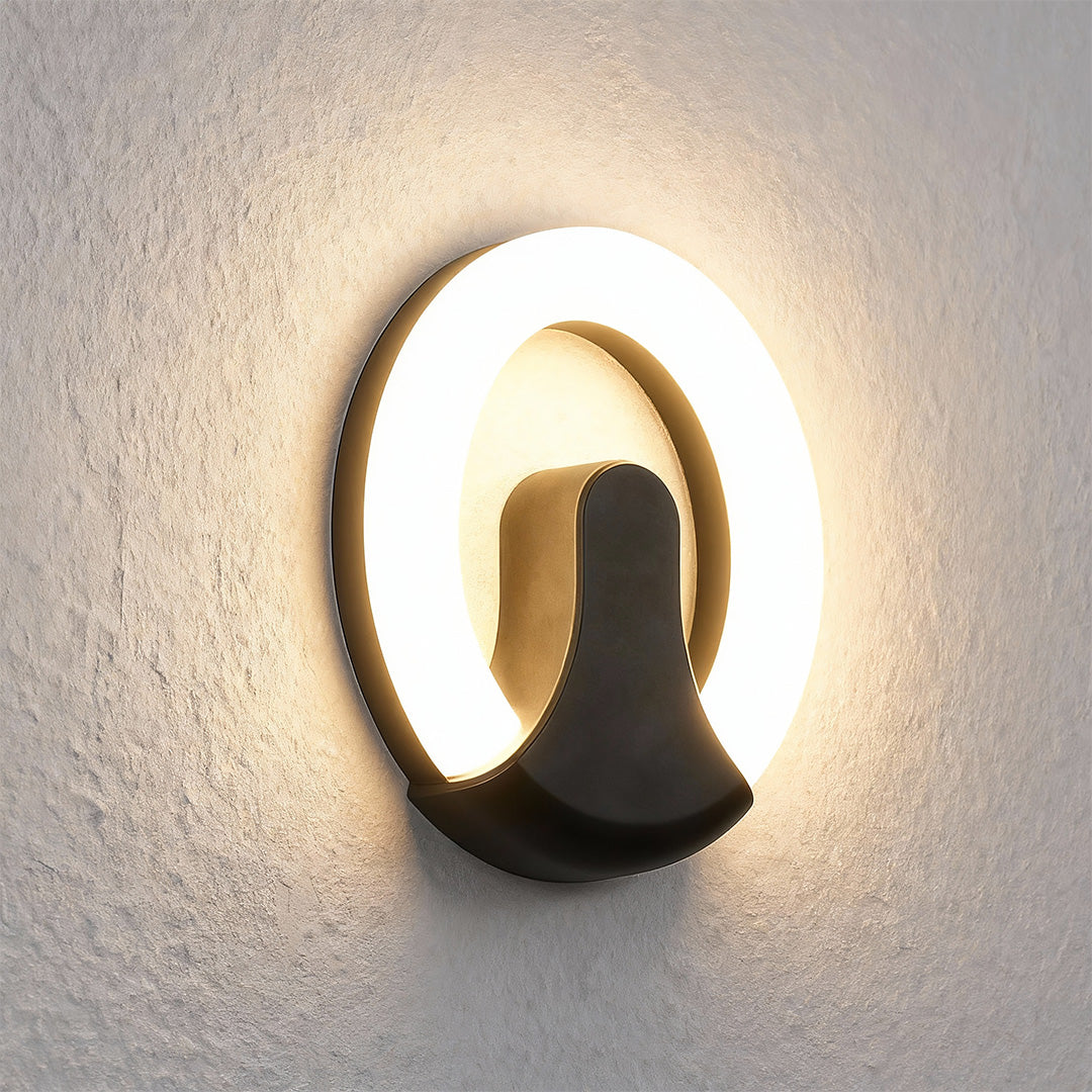 Sophisticated black wall sconce light featuring glass shade chandelier influence with striking circular illumination on neutral facade.