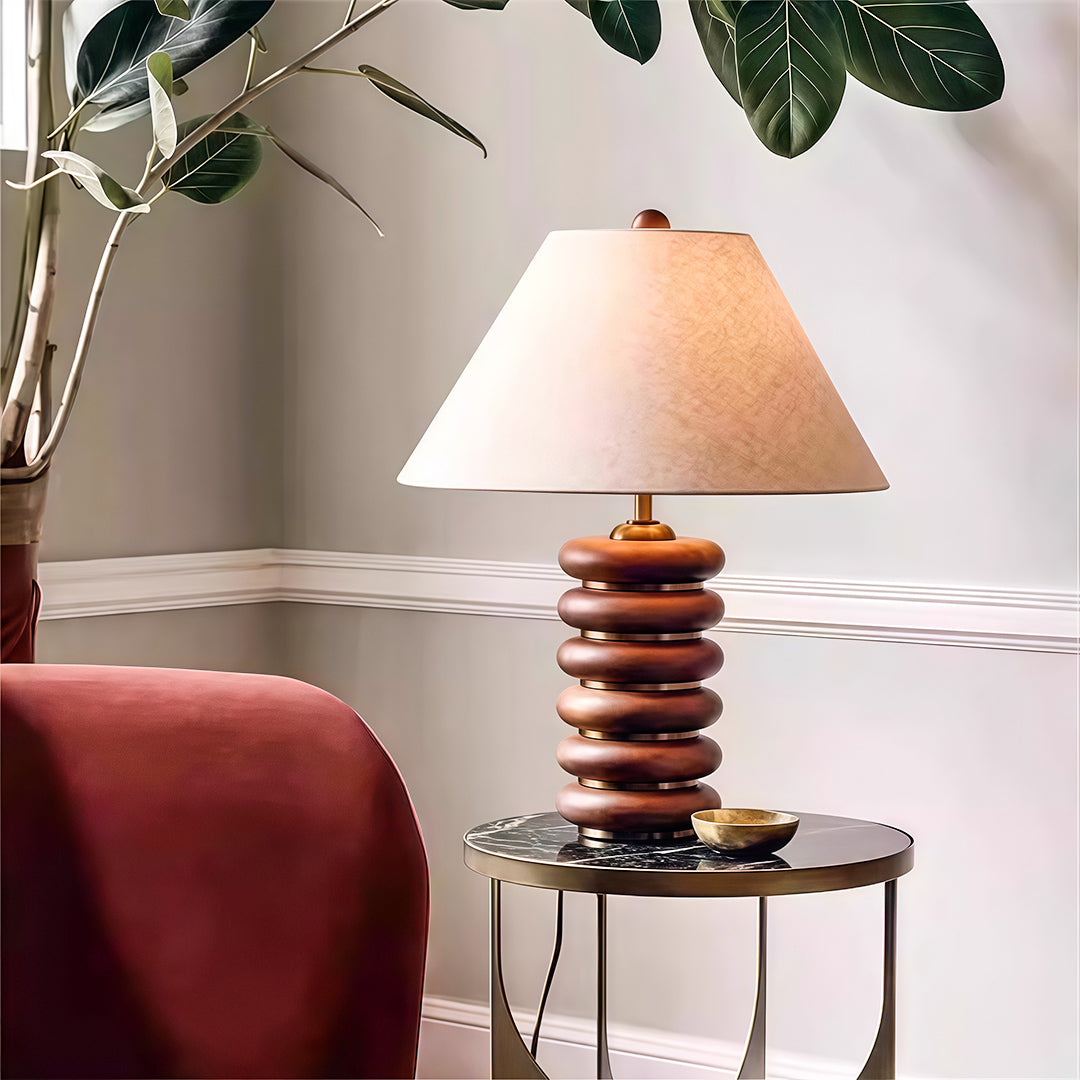Sophisticated cloth table lamp featuring glass shade chandelier influence illuminating modern living room with pink velvet chair.