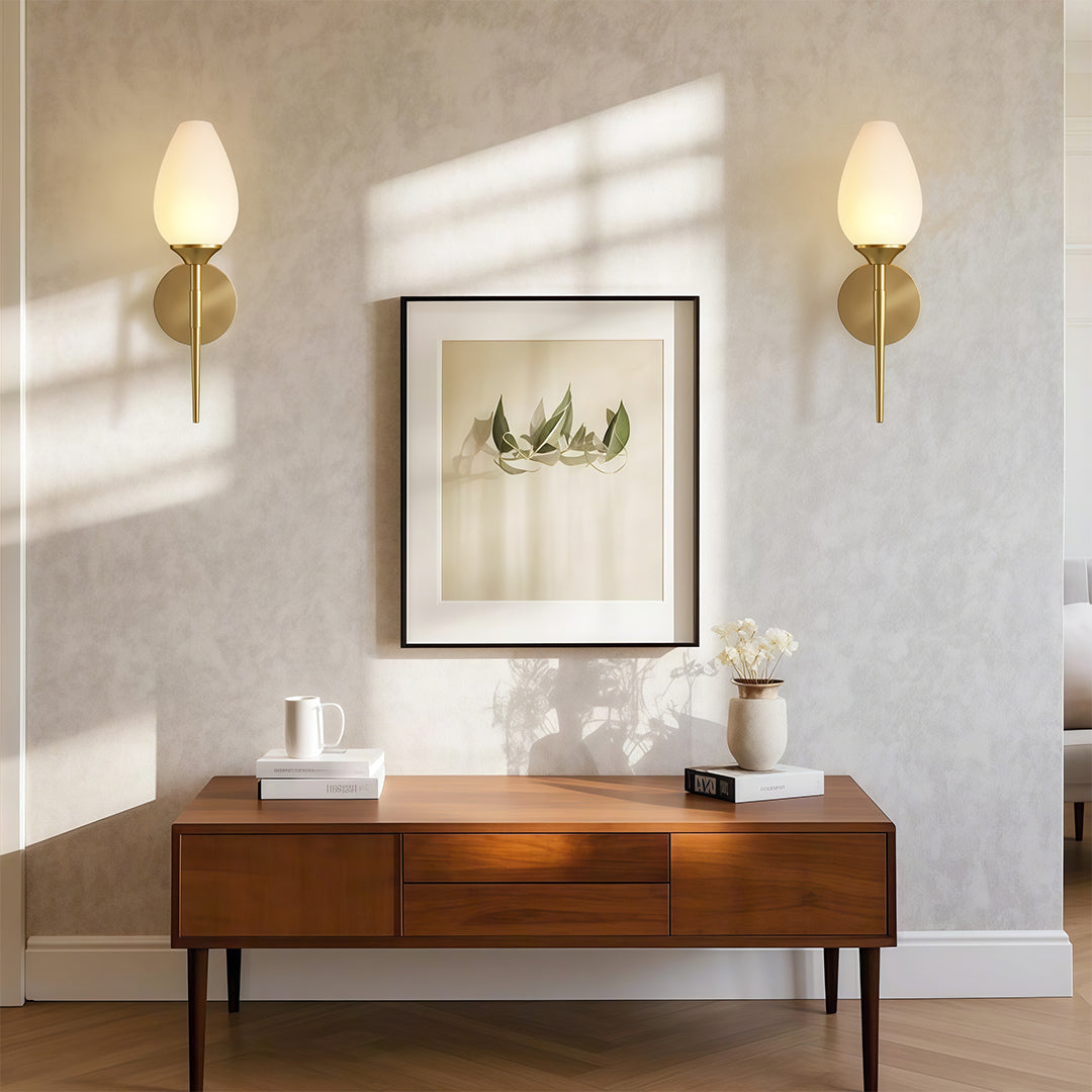 Sophisticated glass wall lights with glass shade chandelier influence illuminating modern bathroom in symmetrical arrangement.