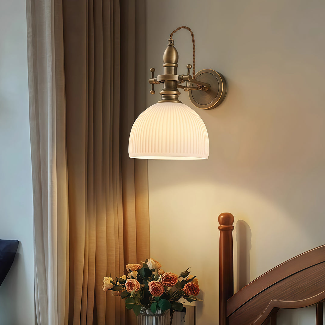 Sophisticated indoor wall mount lights with glass shade chandelier influence providing soft task lighting on neutral wall beside curtains.