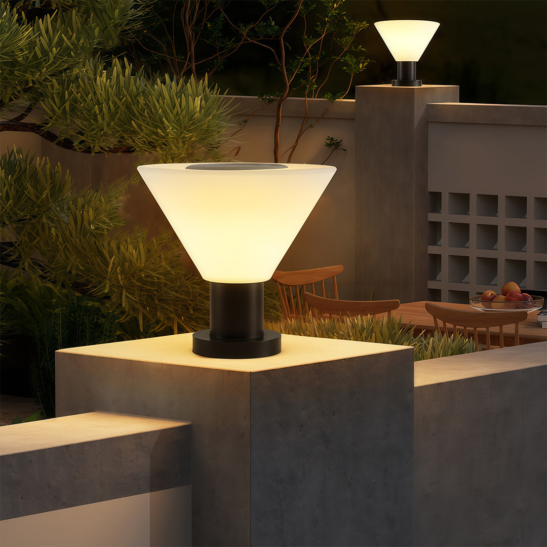 Sophisticated landscape pillar lighting with glass shade chandelier influence providing decorative accent on contemporary pillar caps.