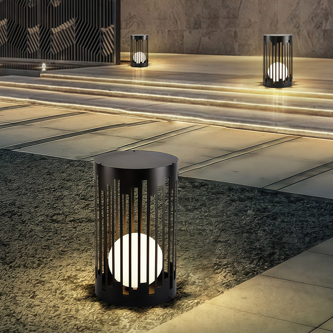 Sophisticated outdoor lantern light with glass shade chandelier design providing accent lighting on contemporary gravel pathway.