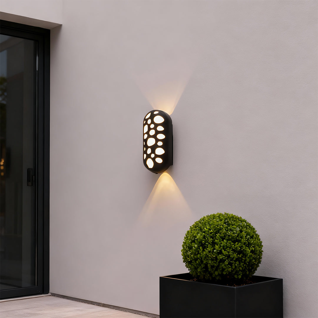 Sophisticated outdoor up down wall lights featuring glass shade chandelier influence with striking light patterns on minimalist facade.