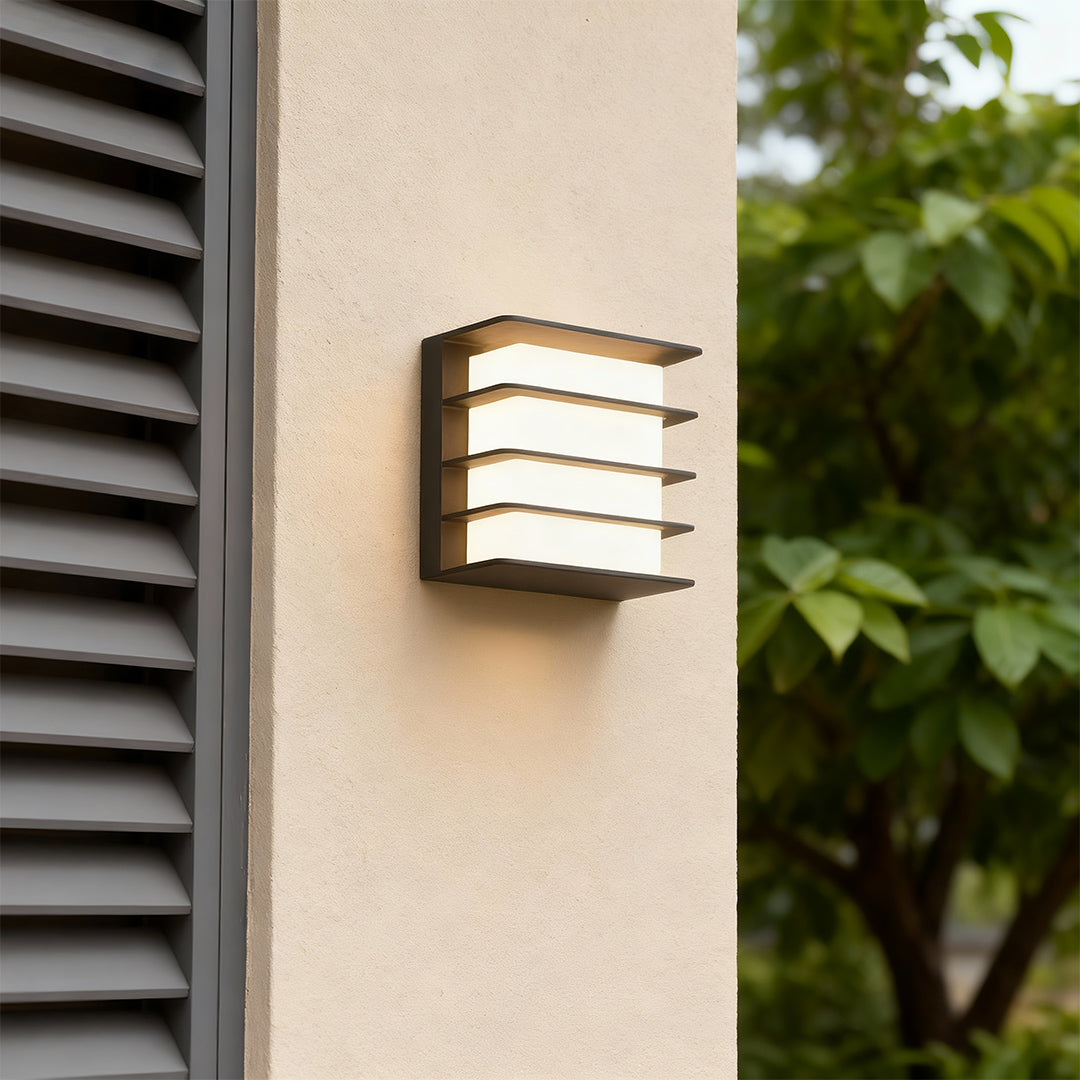 Sophisticated square LED wall lights featuring glass shade chandelier influence with slatted design on neutral facade.