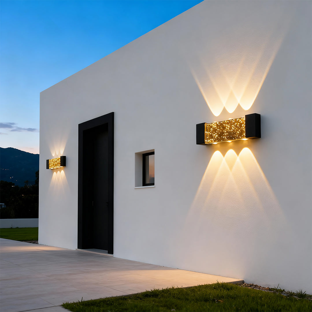Sophisticated up down wall light featuring glass shade chandelier influence with striking light patterns on modern white facade.