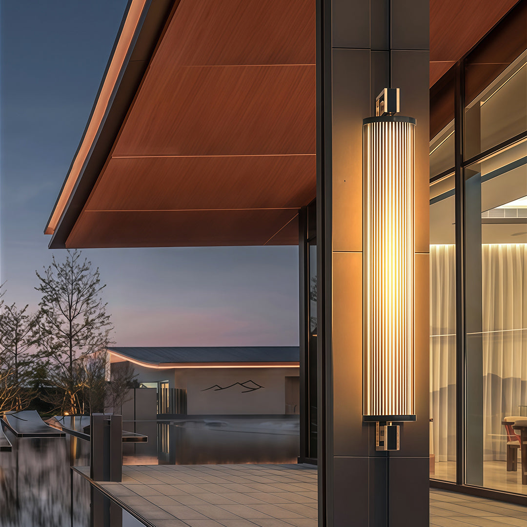 Sophisticated wall mounted linear lighting with glass shade chandelier influence illuminating modern outdoor entrance at twilight.
