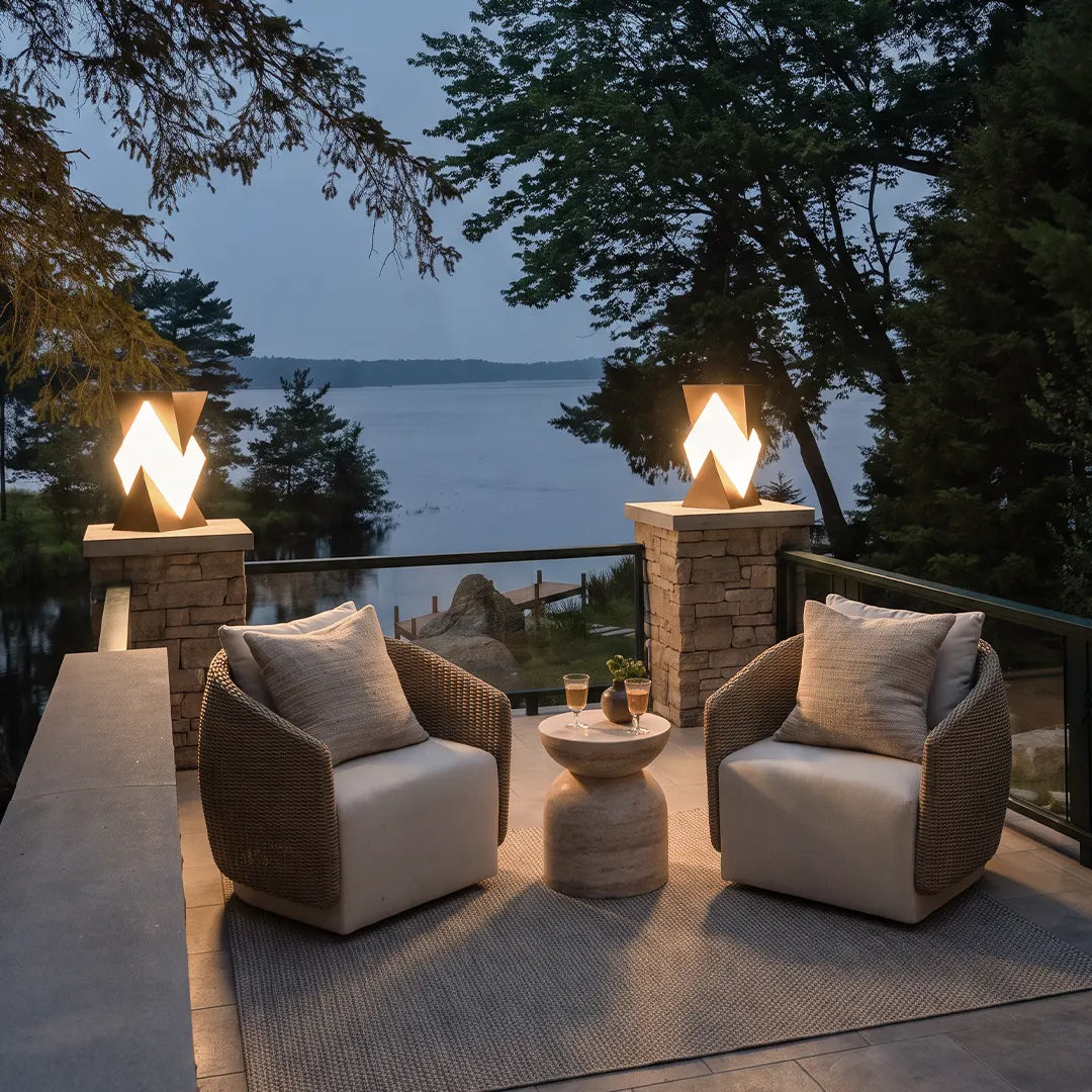 Special shaped pillar light installed on stone gate pillars, creating a warm glow around an outdoor seating area overlooking the water.
