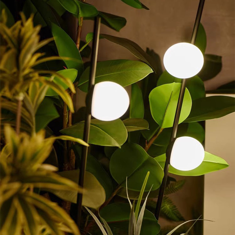 Illuminated spherical garden lights creating warm ambiance among tropical plants and foliage