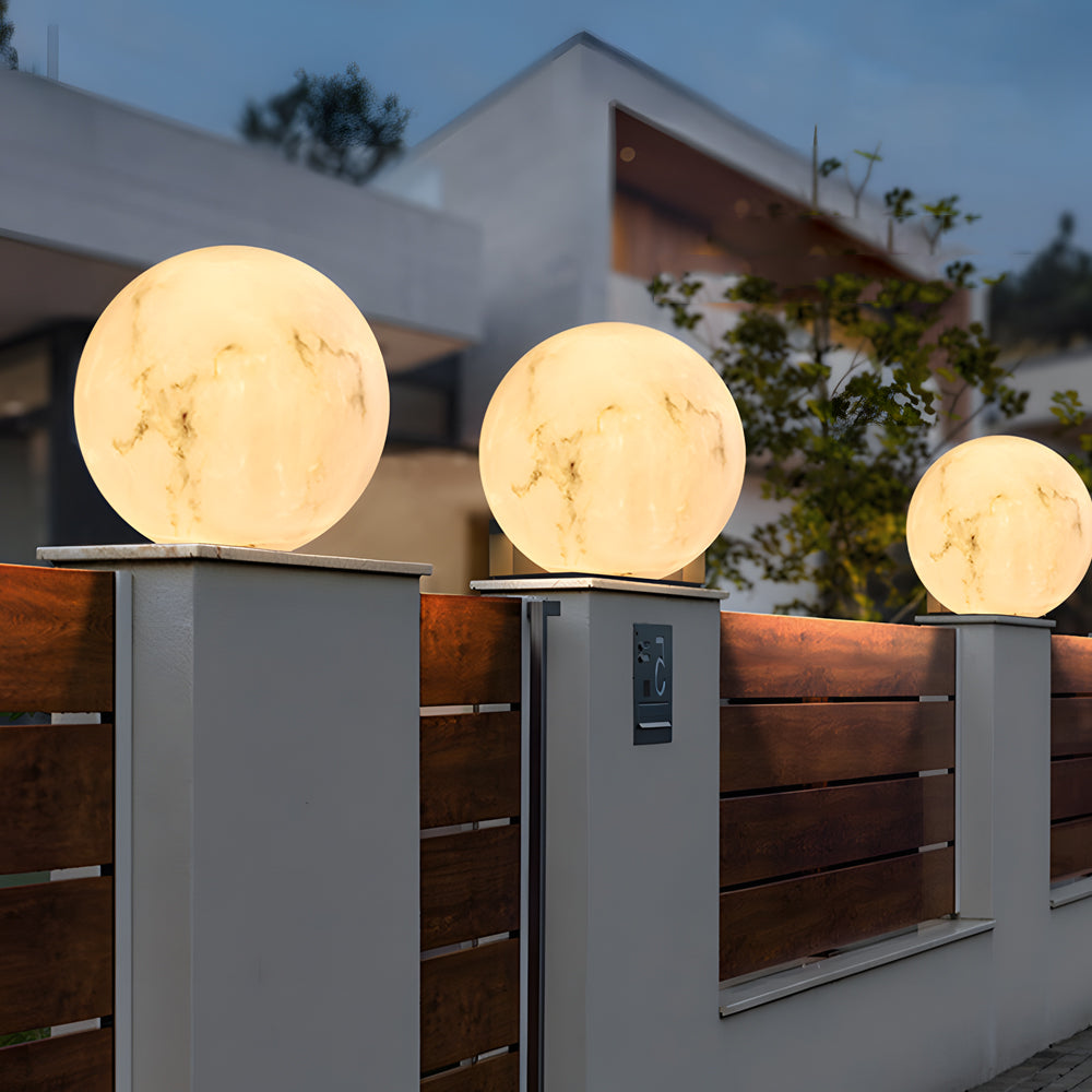 Modern spherical outdoor pillar lights with warm LED glow mounted on concrete pillars creating elegant landscape lighting design