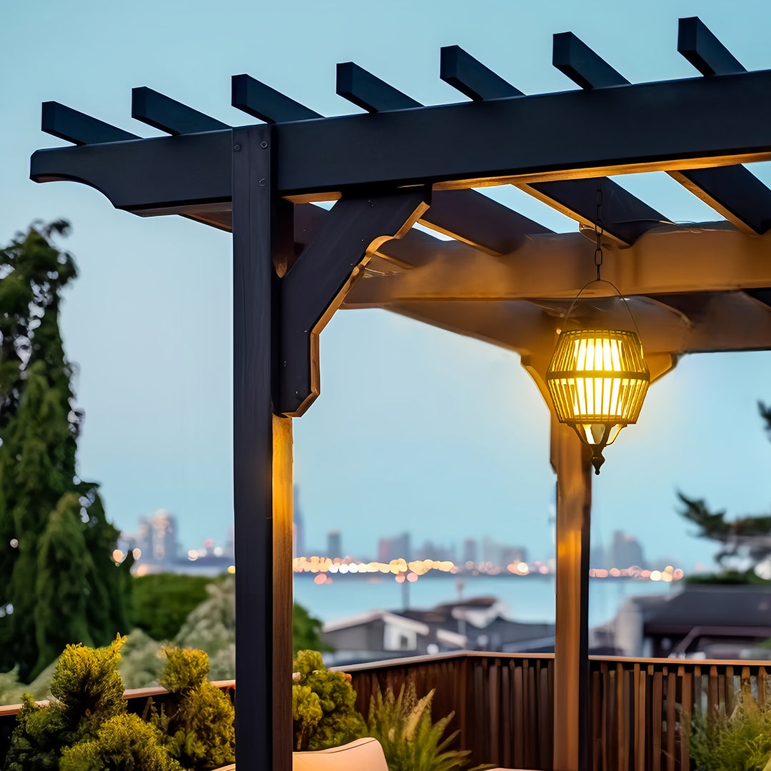 Spherical japanese lantern pendant light suspended under a dark pergola, featuring a warm glow against a distant cityscape.