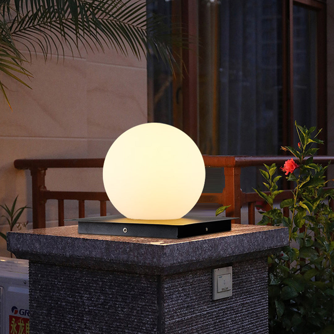Silver Metal Table Lamp spherical pillar light with warm illumination positioned on dark stone surface in modern setting