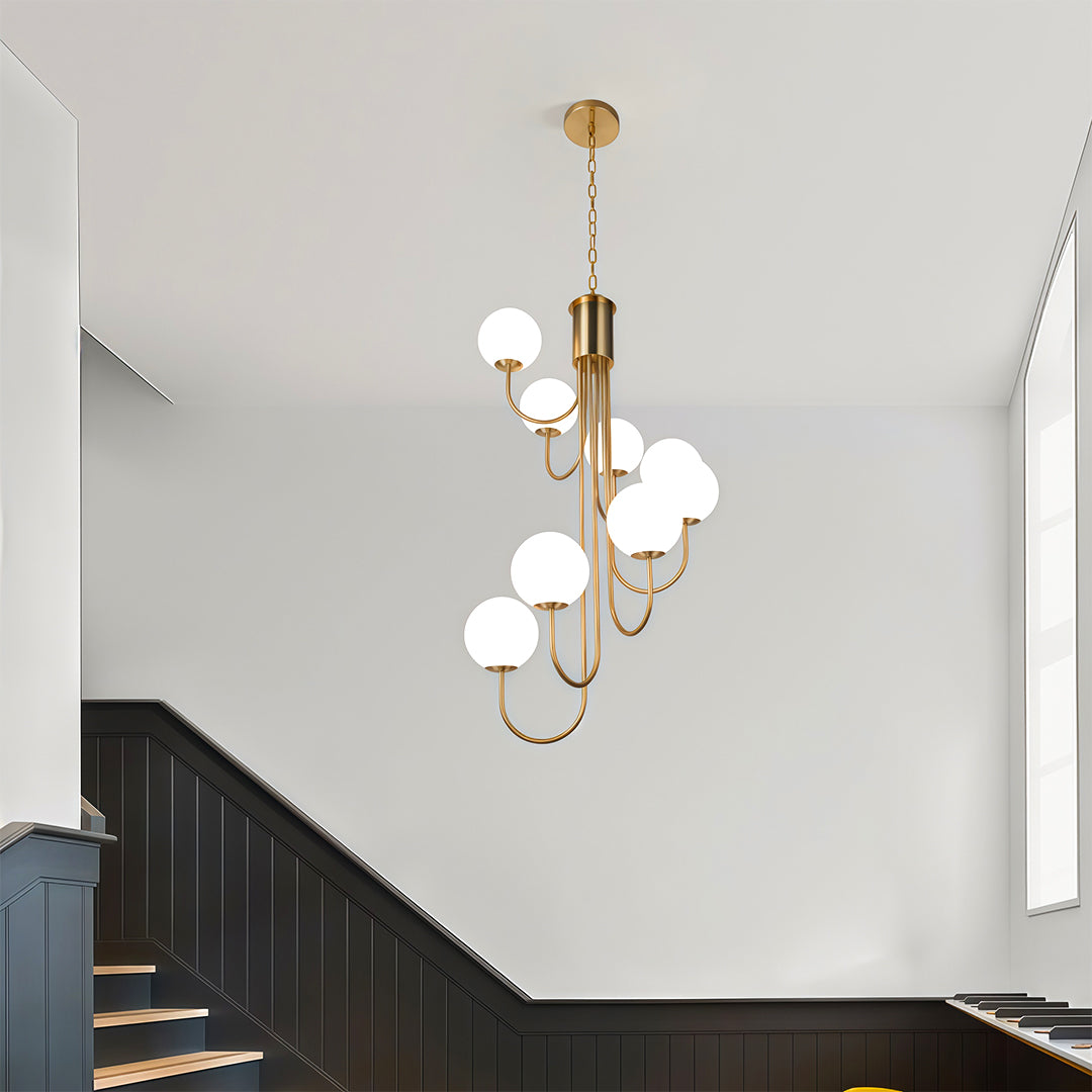 Modern spiral globe chandelier with gold finish hanging elegantly in a stairwell space.