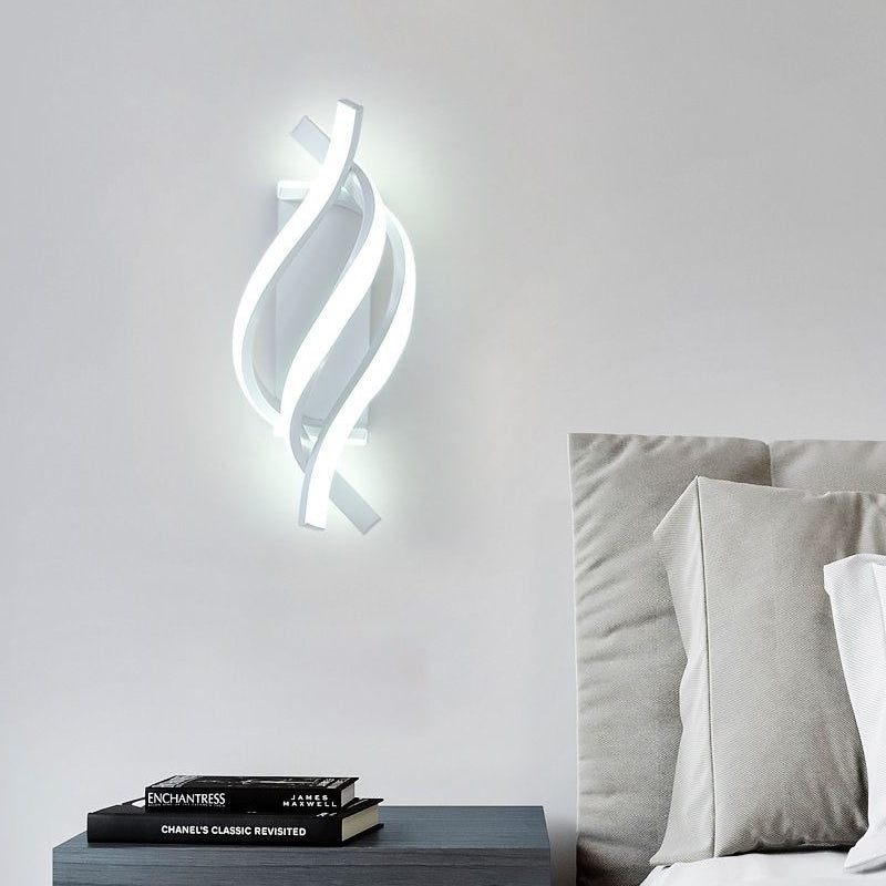 Spiral wall sconce casting a gentle glow in a minimalist bedroom.