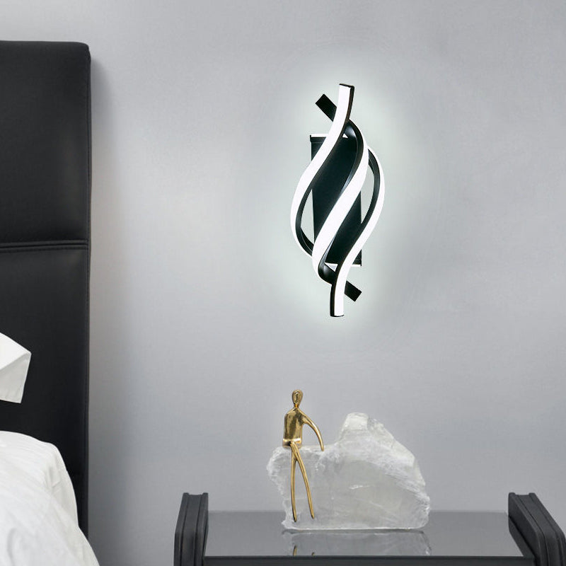 Spiral wall sconce illuminating a modern bedside area with elegant light.