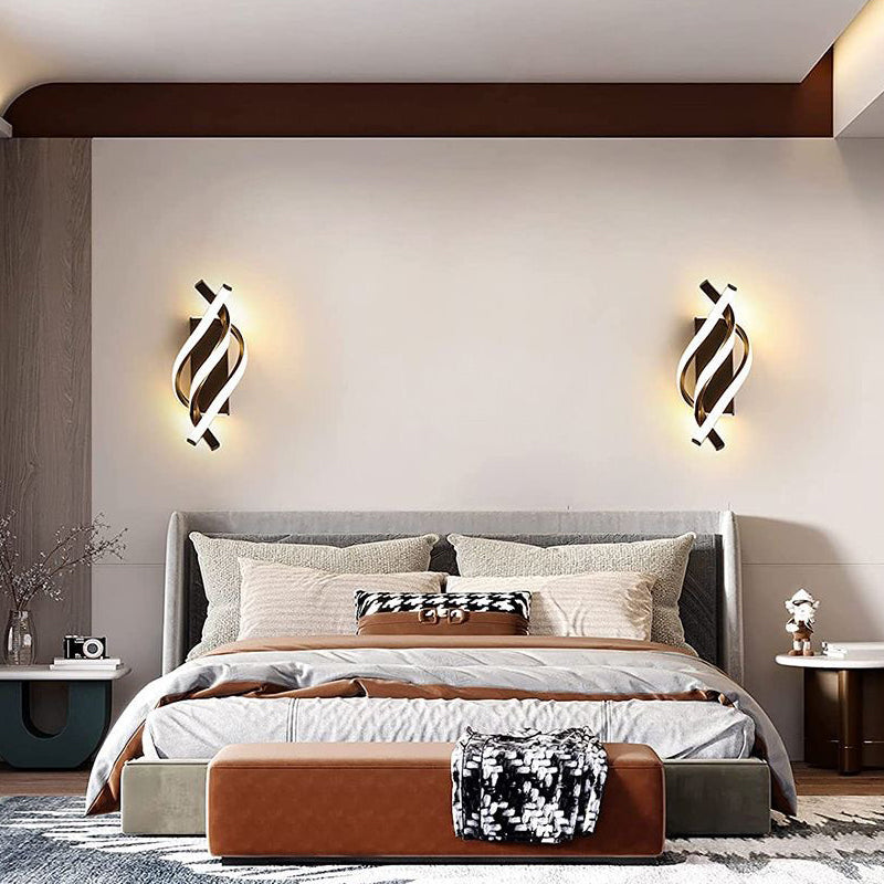 Spiral wall sconce providing warm light beside a stylish bed.