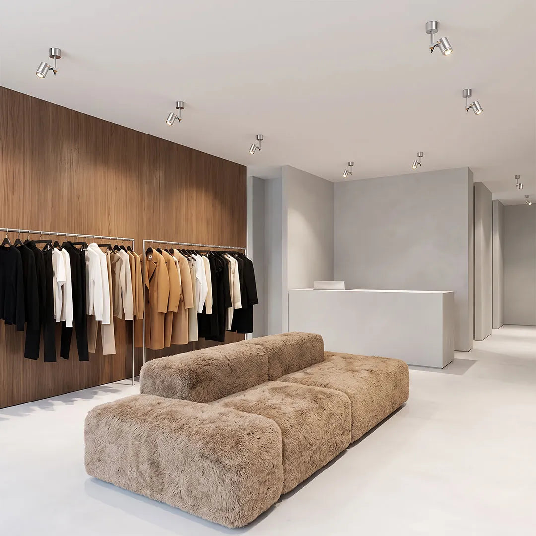 Spotlight ceiling light providing focused illumination in a minimalist clothing showroom.