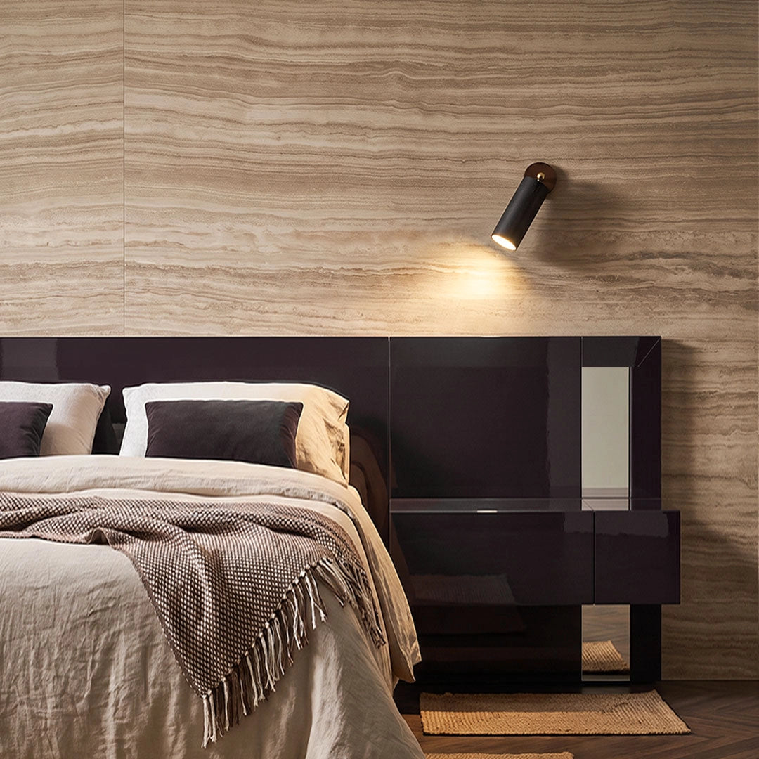 Spotlight wall lights casting focused light above a modern bed against a textured wood wall.