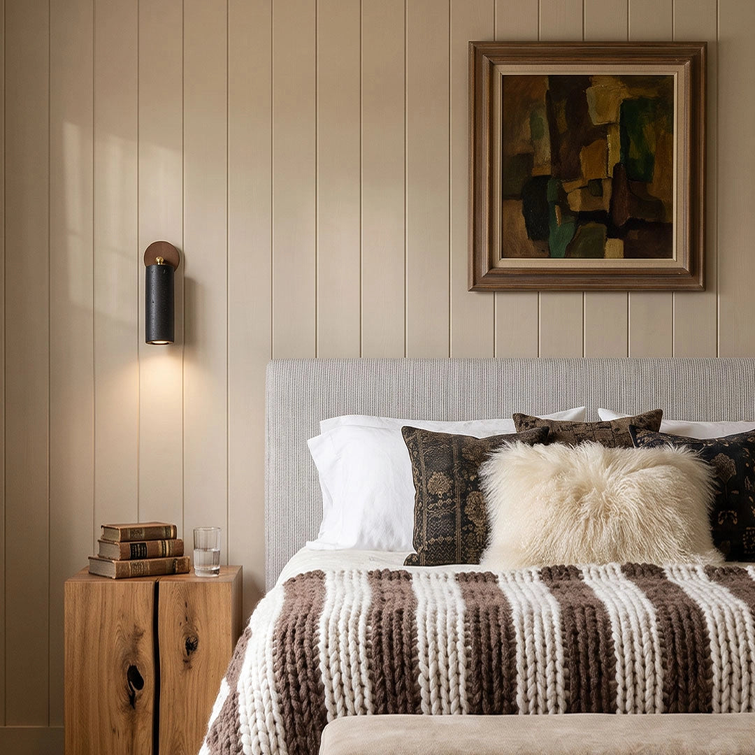 Spotlight wall lights mounted beside a bed in a warm neutral bedroom with wood furniture.