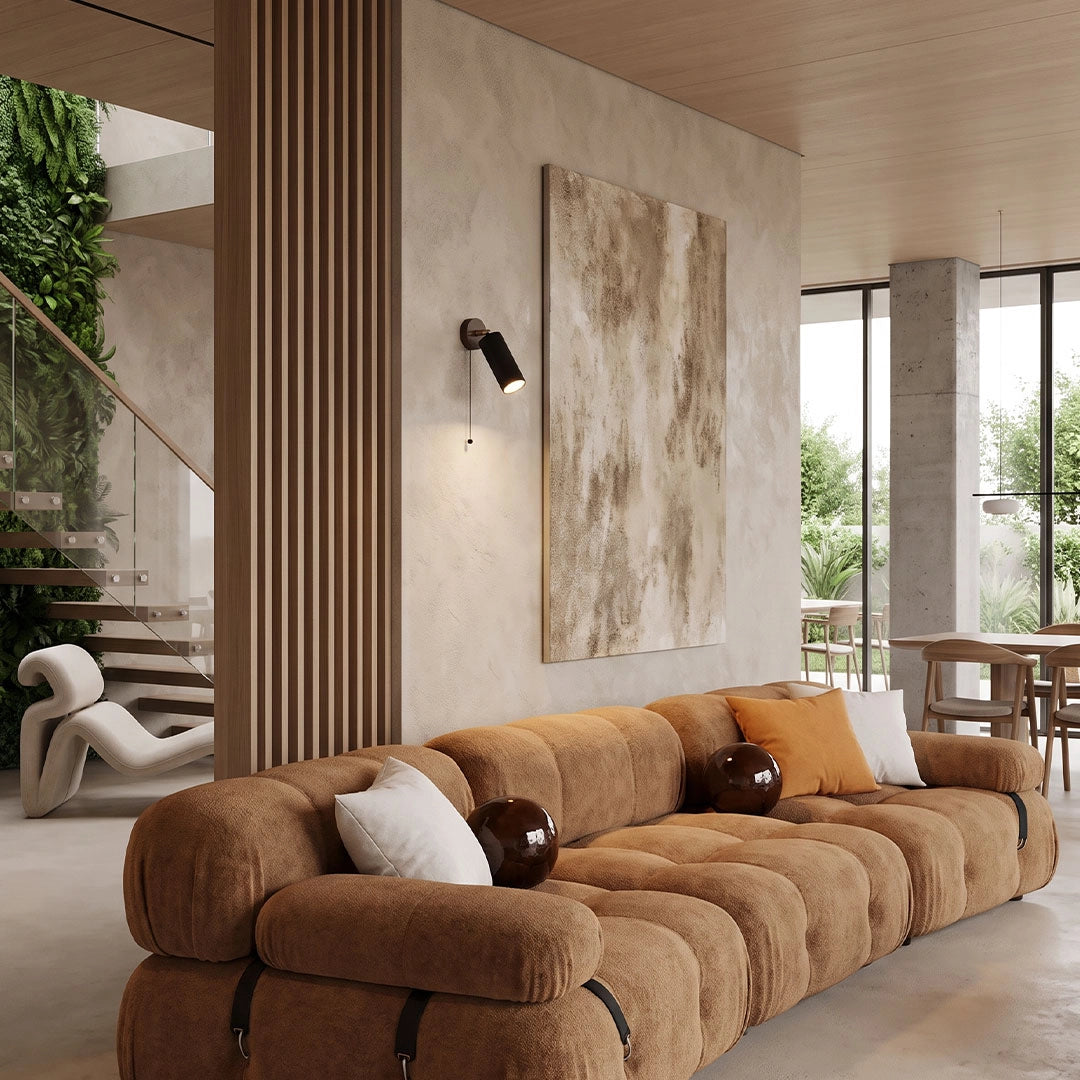 Spotlight wall lights mounted above a brown sectional sofa in a modern open-plan living room.