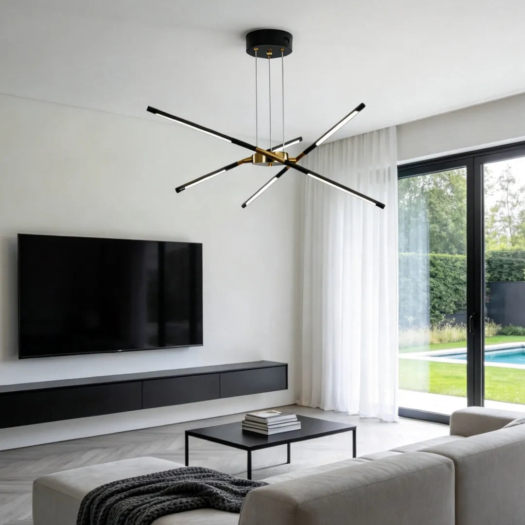 Sputnik chandelier with a black canopy and slim crossed light arms mounted in a minimalist living room with a wall-mounted television.