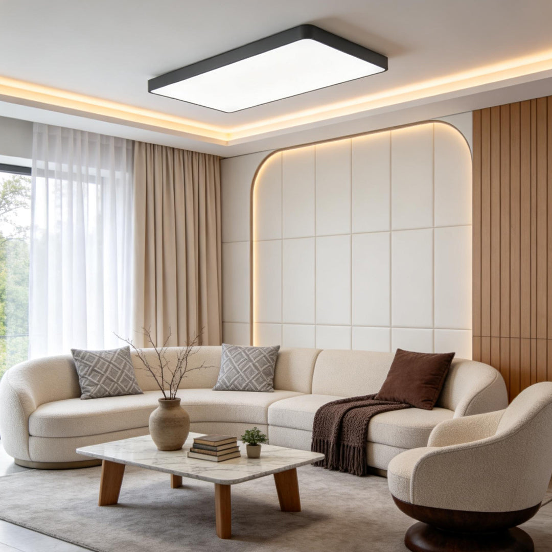 Square ceiling light with a dark frame mounted in a contemporary living room with curved seating and warm cove lighting.