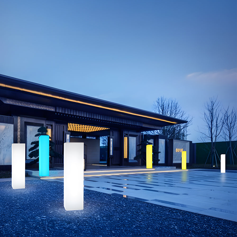 Square floor lamp in blue light, displayed in front of a modern building entrance.