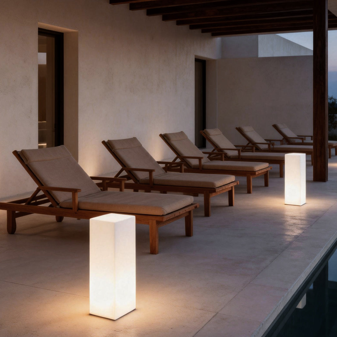 Square floor lamp illuminating a modern outdoor lounge area with sunbeds and a pool.