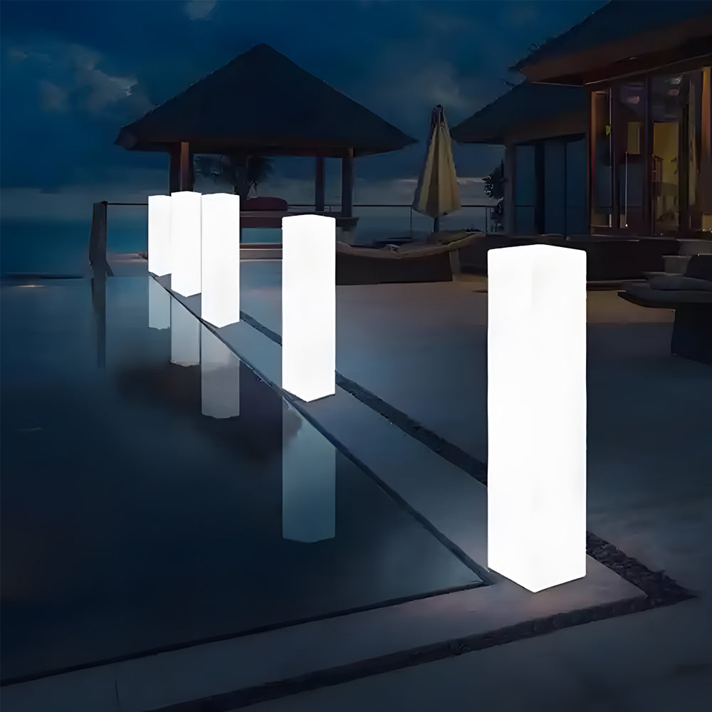 Square floor lamp illuminating a serene poolside setting with water reflections.