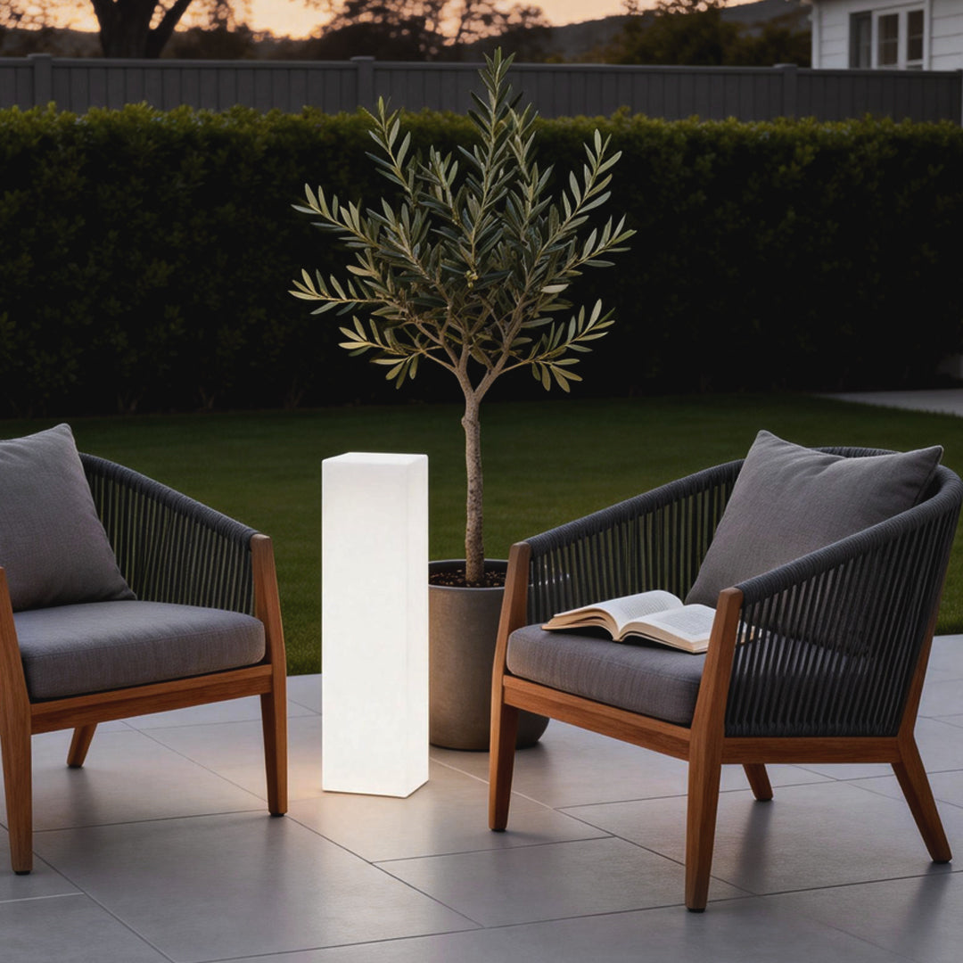 Square floor lamp providing soft light beside a gray outdoor armchair and potted plant.