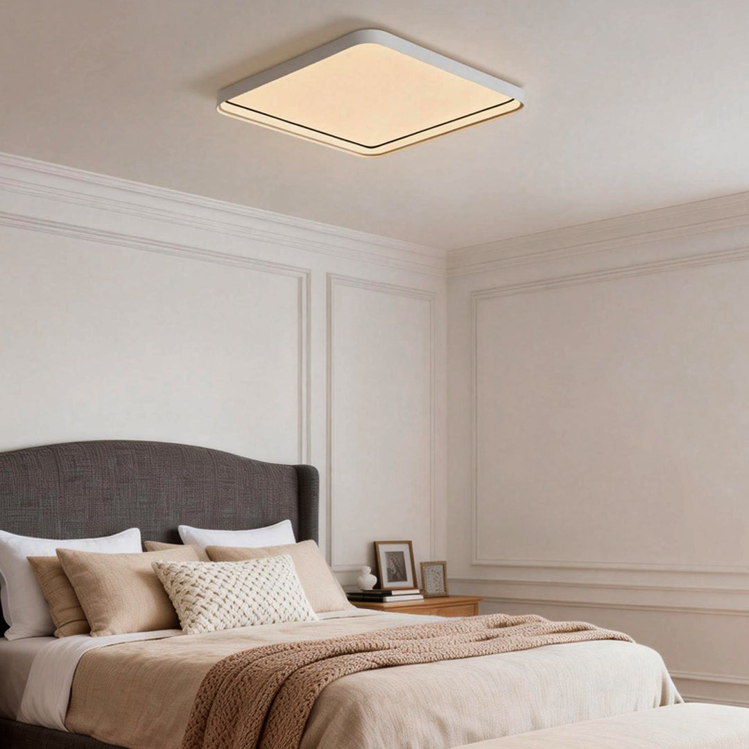 Square flush mount ceiling light installed in a neutral bedroom interior.