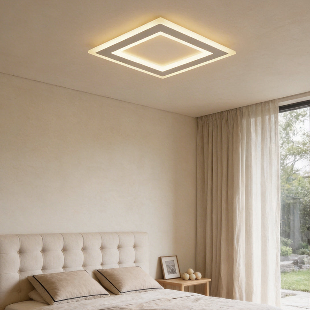 Square flush mount light providing soft illumination in a modern bedroom with large windows.