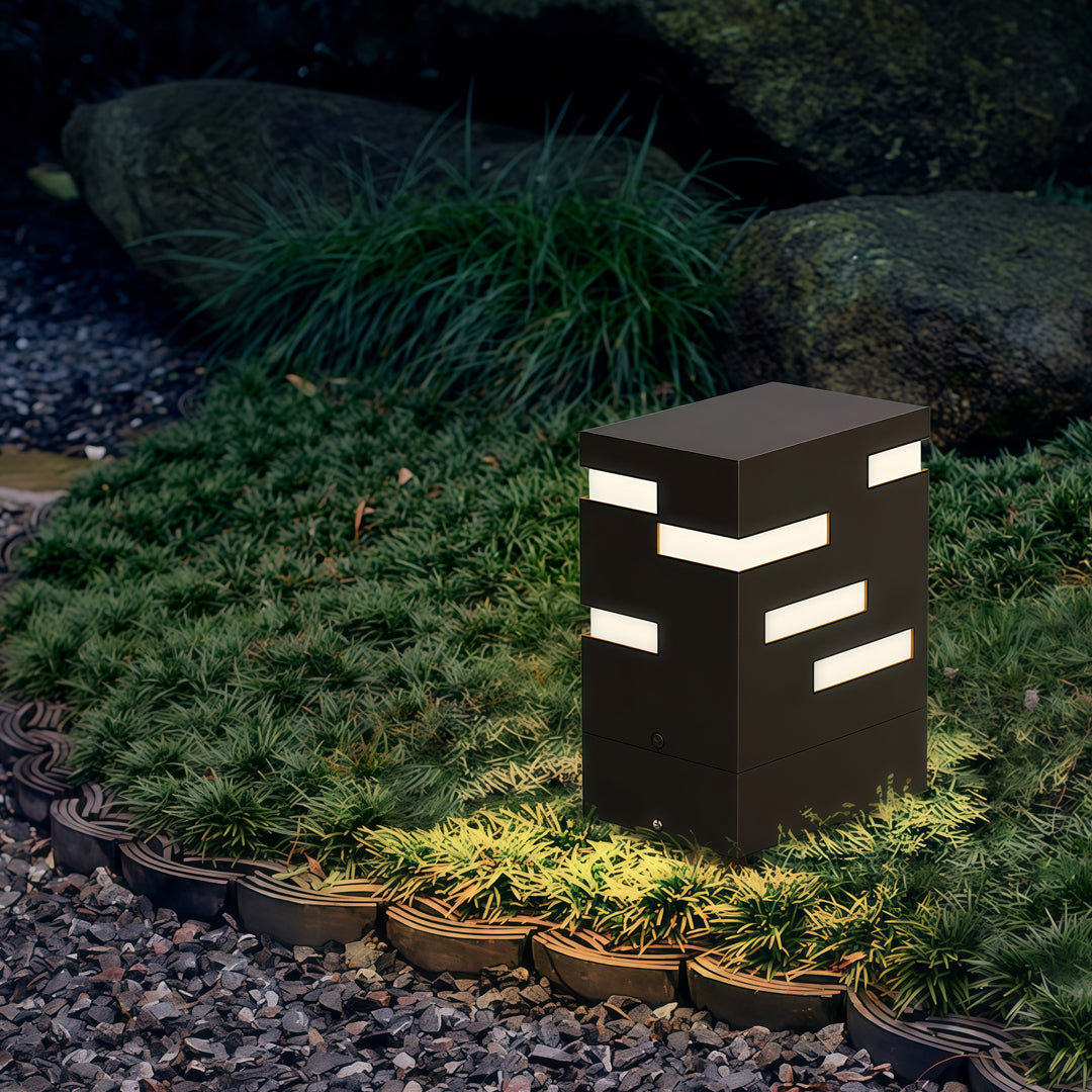 Square black led bollard lights illuminating garden greenery, offering contemporary layered lighting for outdoor environments.