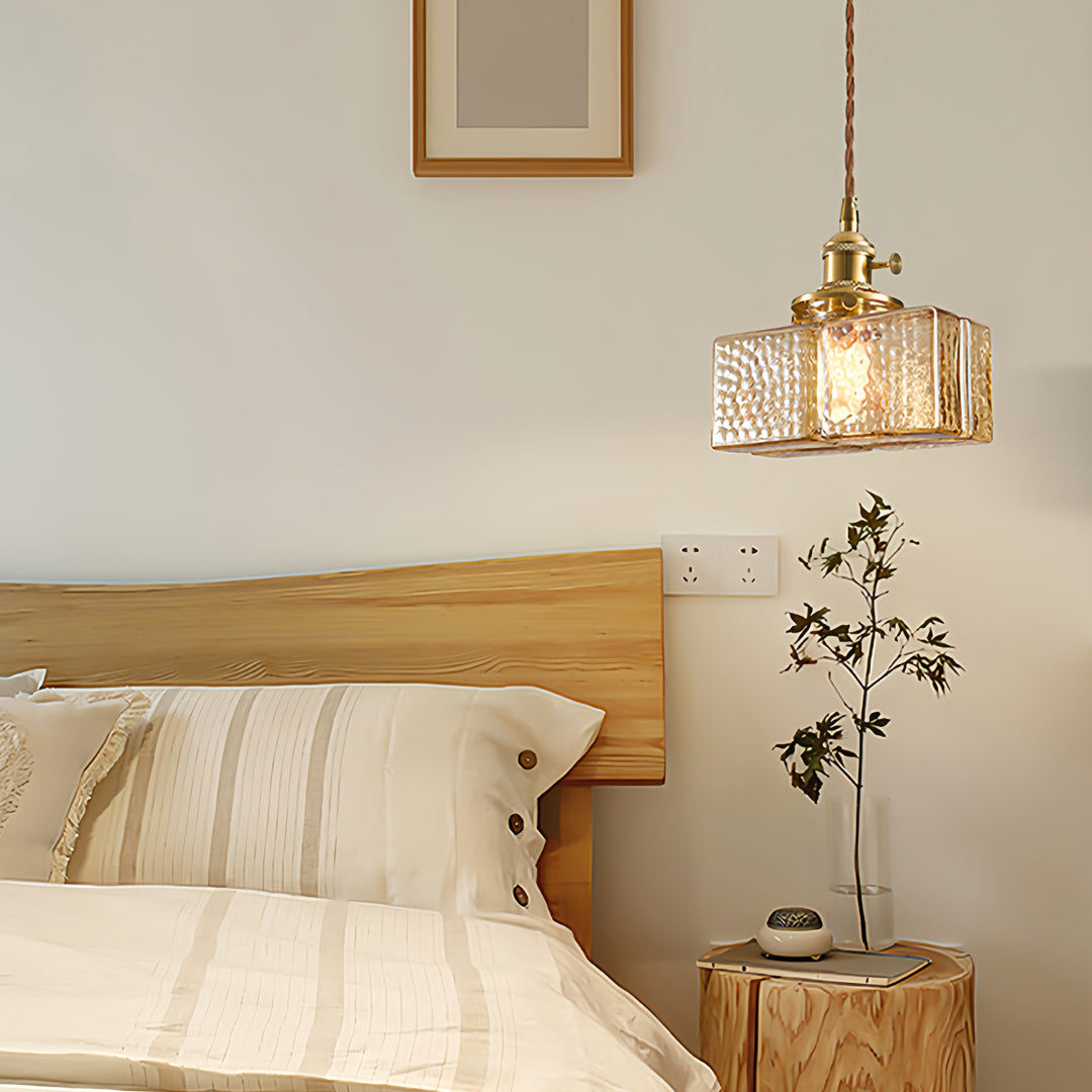 Square glass pendant light illuminating contemporary kitchen island with warm brass accents and neutral tones
