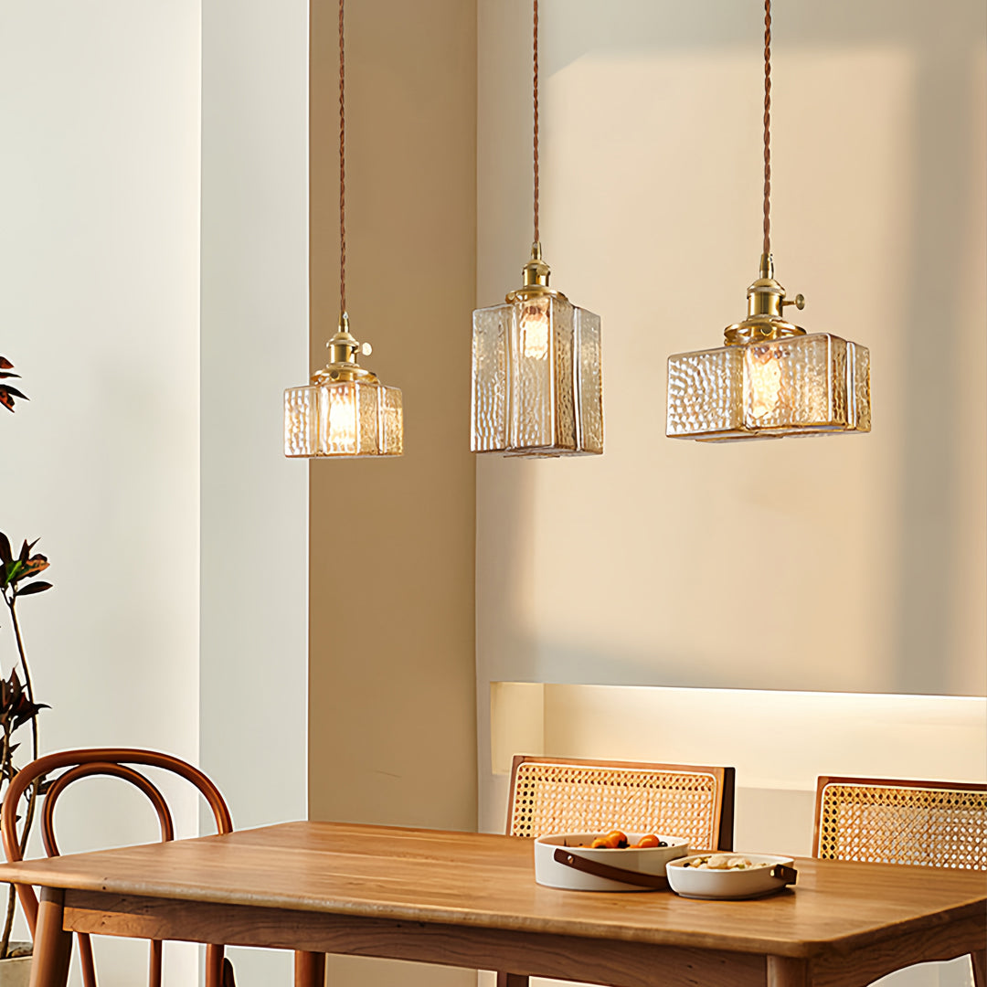 Square glass pendant lights creating ambient lighting in modern dining room with blue accent wall and natural wood